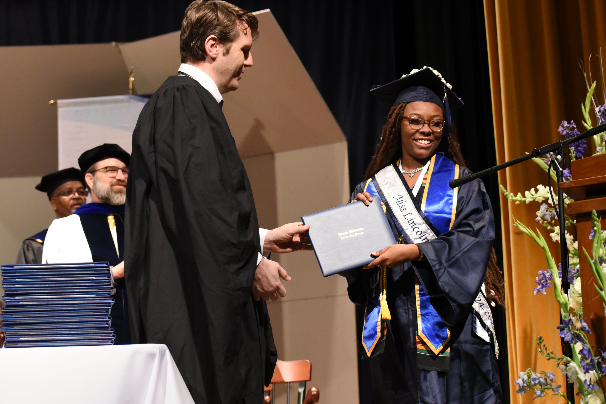 A Lincoln University graduate walks across the stage to recieve their diploma.